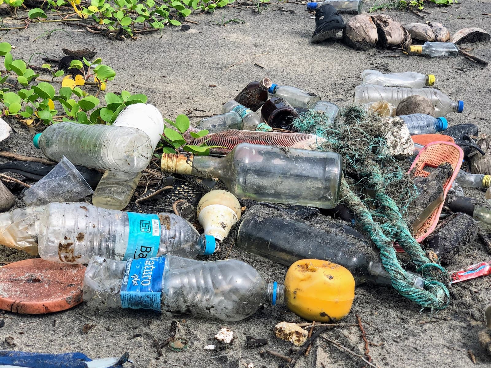 Assorted garbage bottles on a sandy surface