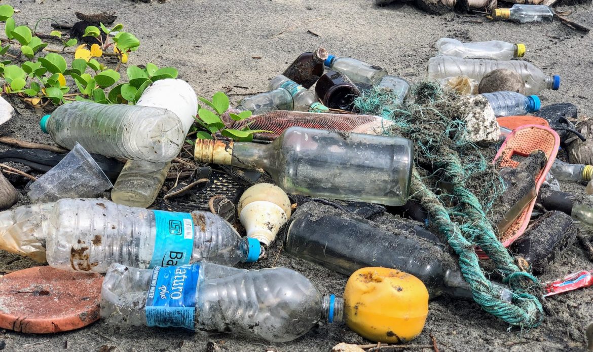 assorted garbage bottles on sandy surface